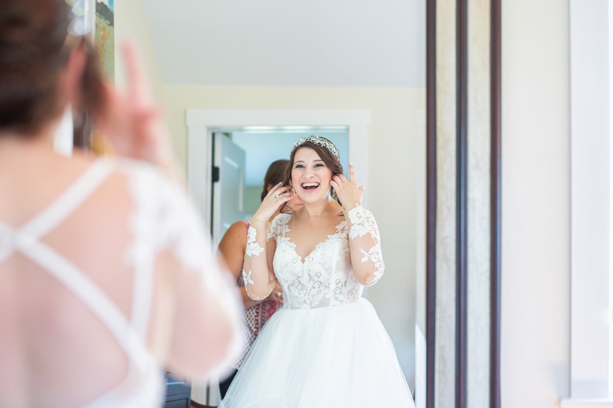 Bride sees herself in the mirror and has a joyful expression and laugh.