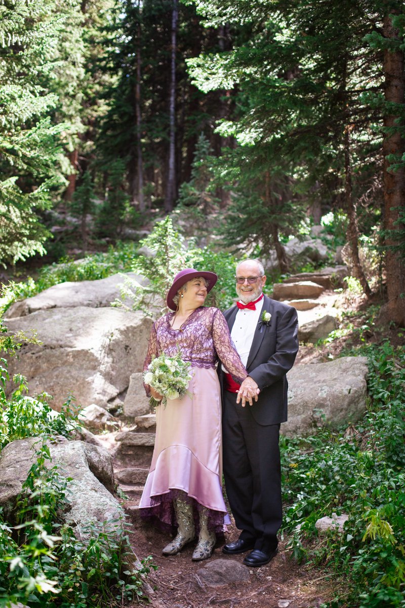 Mature couple wearing purple and red hues in the alpine forest on their favorite hiking trail