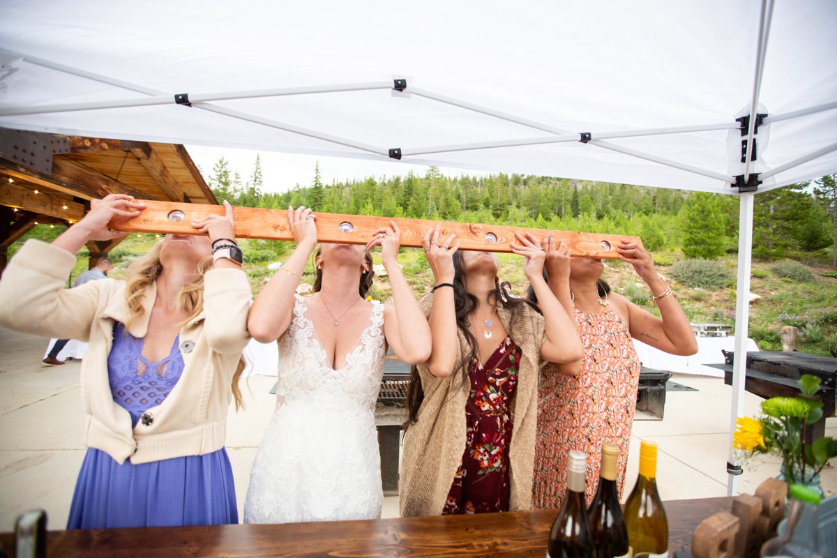 Bride and a group of wedding guests throwing back a shot ski at the bar.