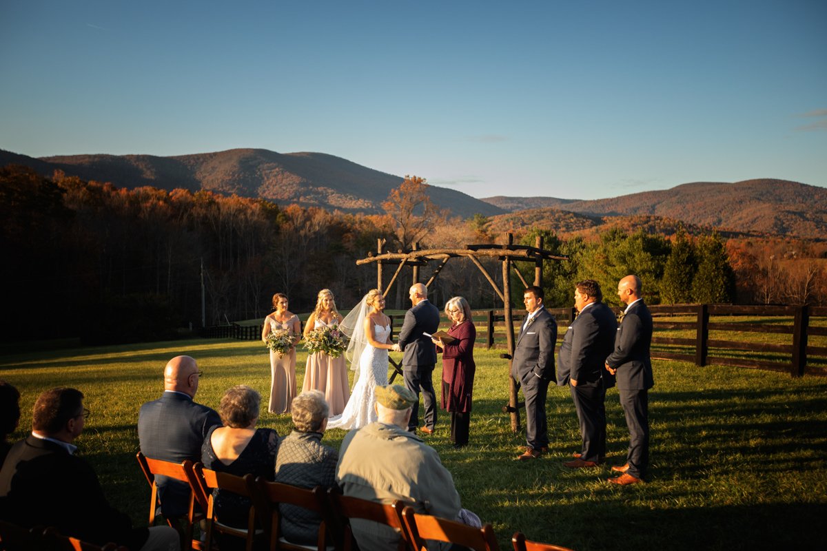 Couple exchanging vows on a hillside with mountains surrounding them. The light is low. The season is fall.