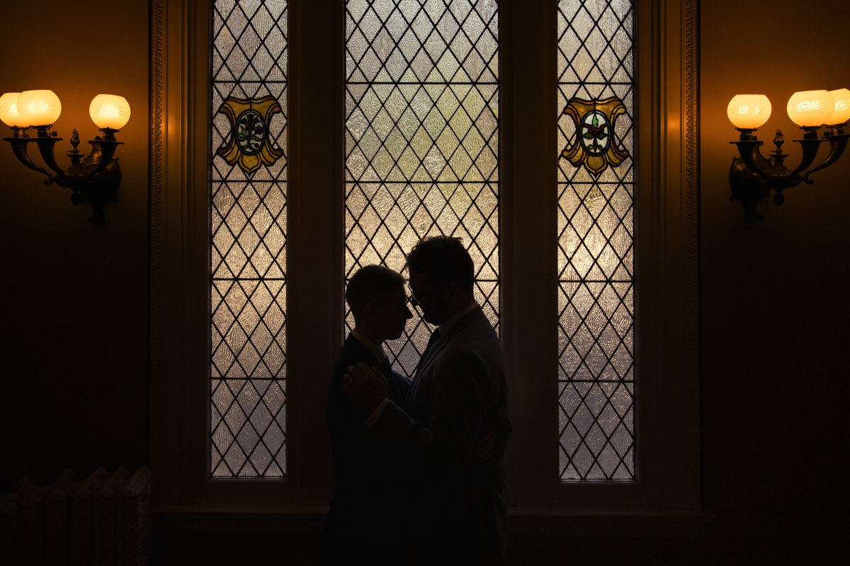 Silhouette of a couple in front of a stained glas window.