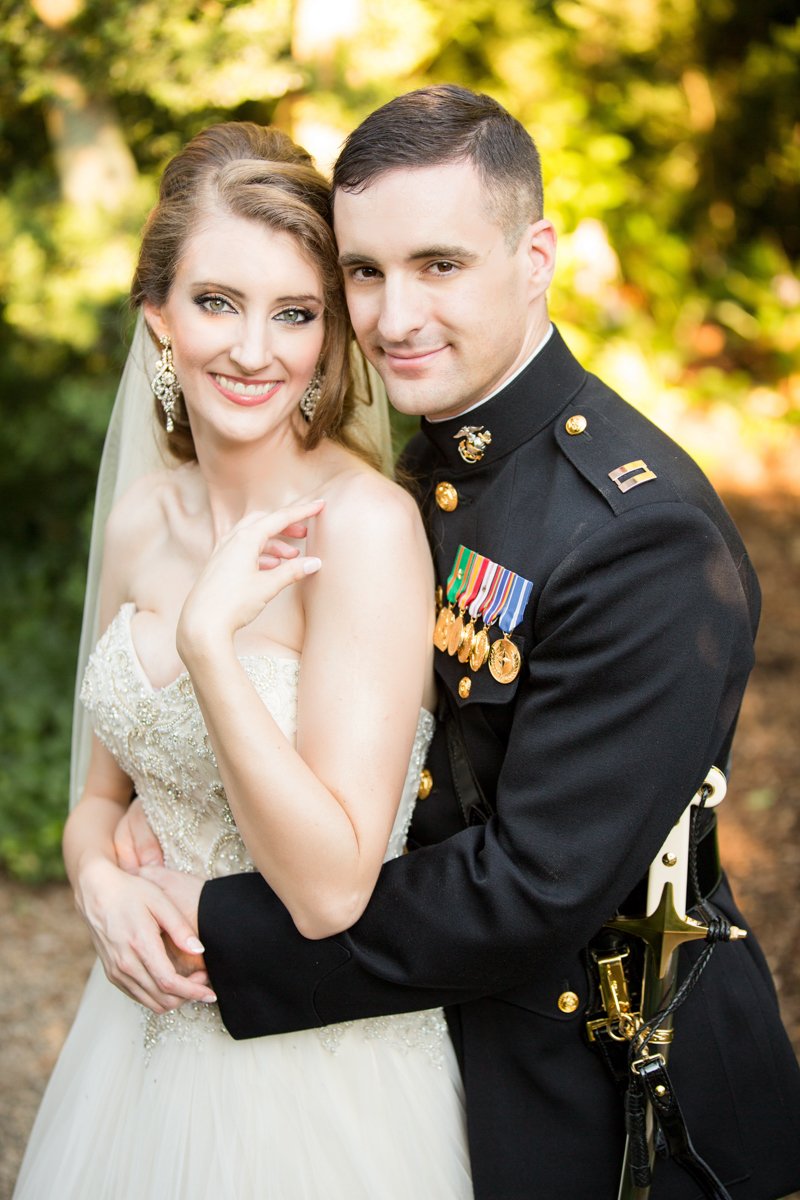 A couple embrace and look at the camera smiling. the groom is in his dress military uniform.