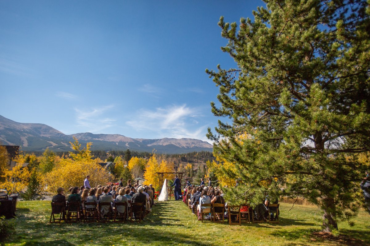 wide, scene setting image of a wedding ceremony in the mountains at fall.