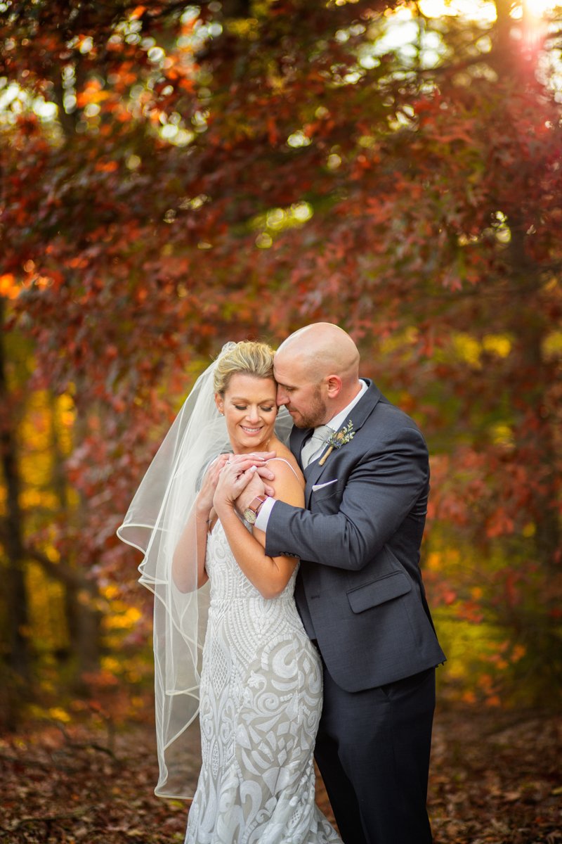 Couple embracing in fall foliage that is backlight. Tones are yellow and red.