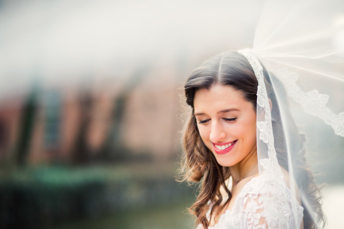 Bride smiling to herself as the veil blows in the wind.