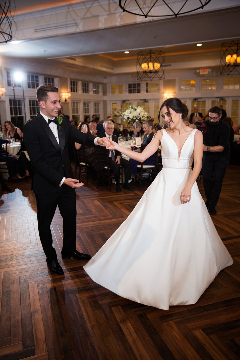 Groom and bride dance their first dance on a ballroom floor.
