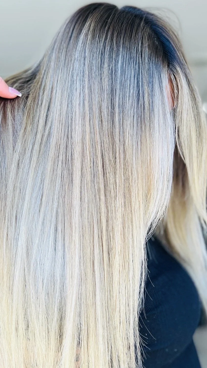Close-up of a person's long, straight, blonde hair with darker roots.
