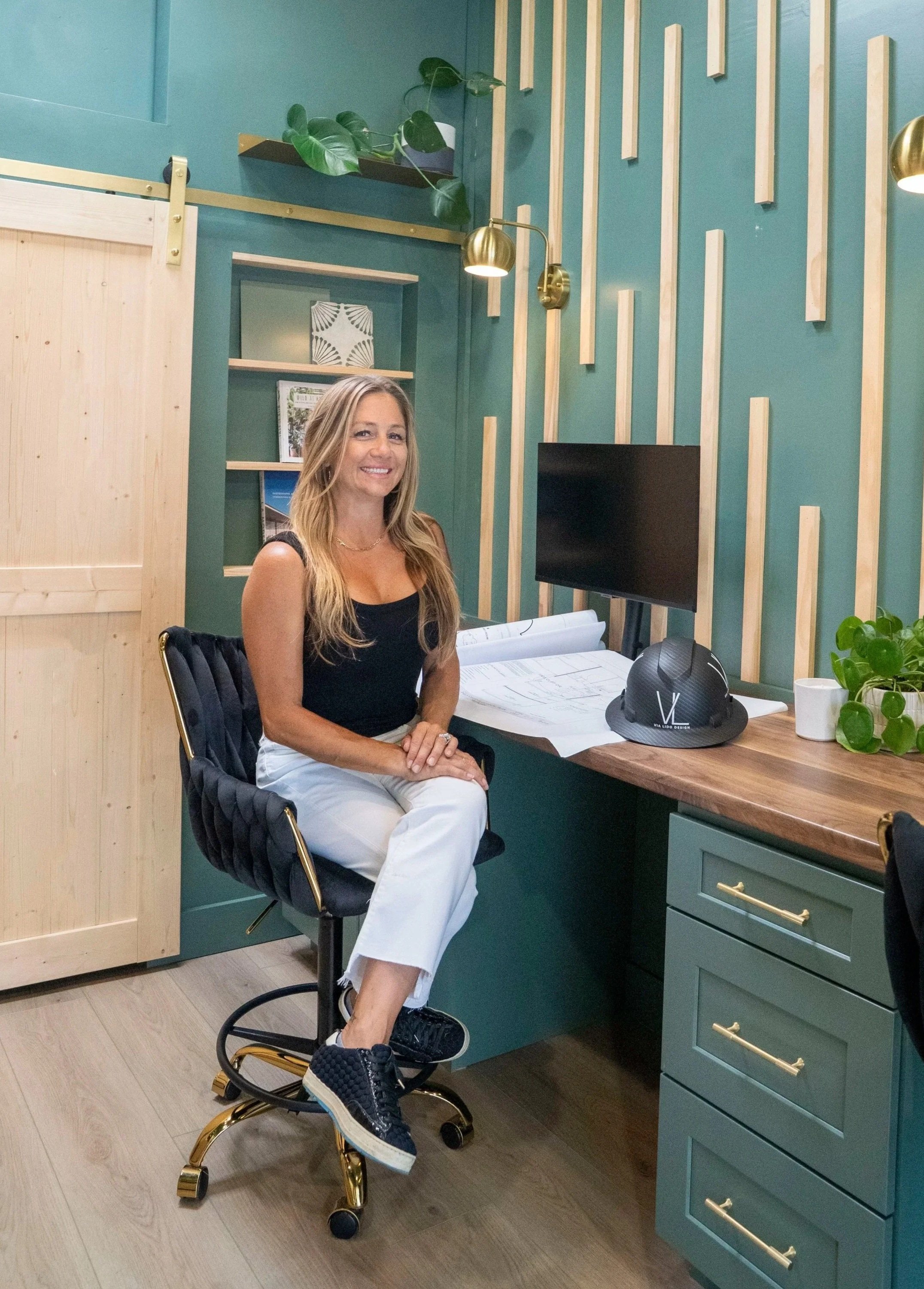 Woman GC sitting in VLD's office.  A modern workspace with green walls and custom wood decor.