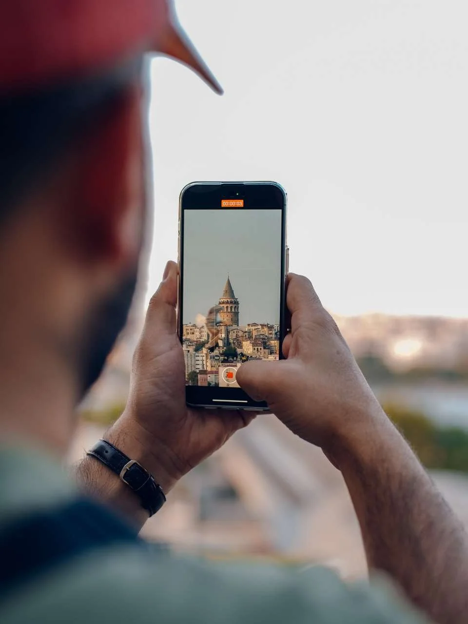 Person taking a photo of the Galata Tower with a smartphone