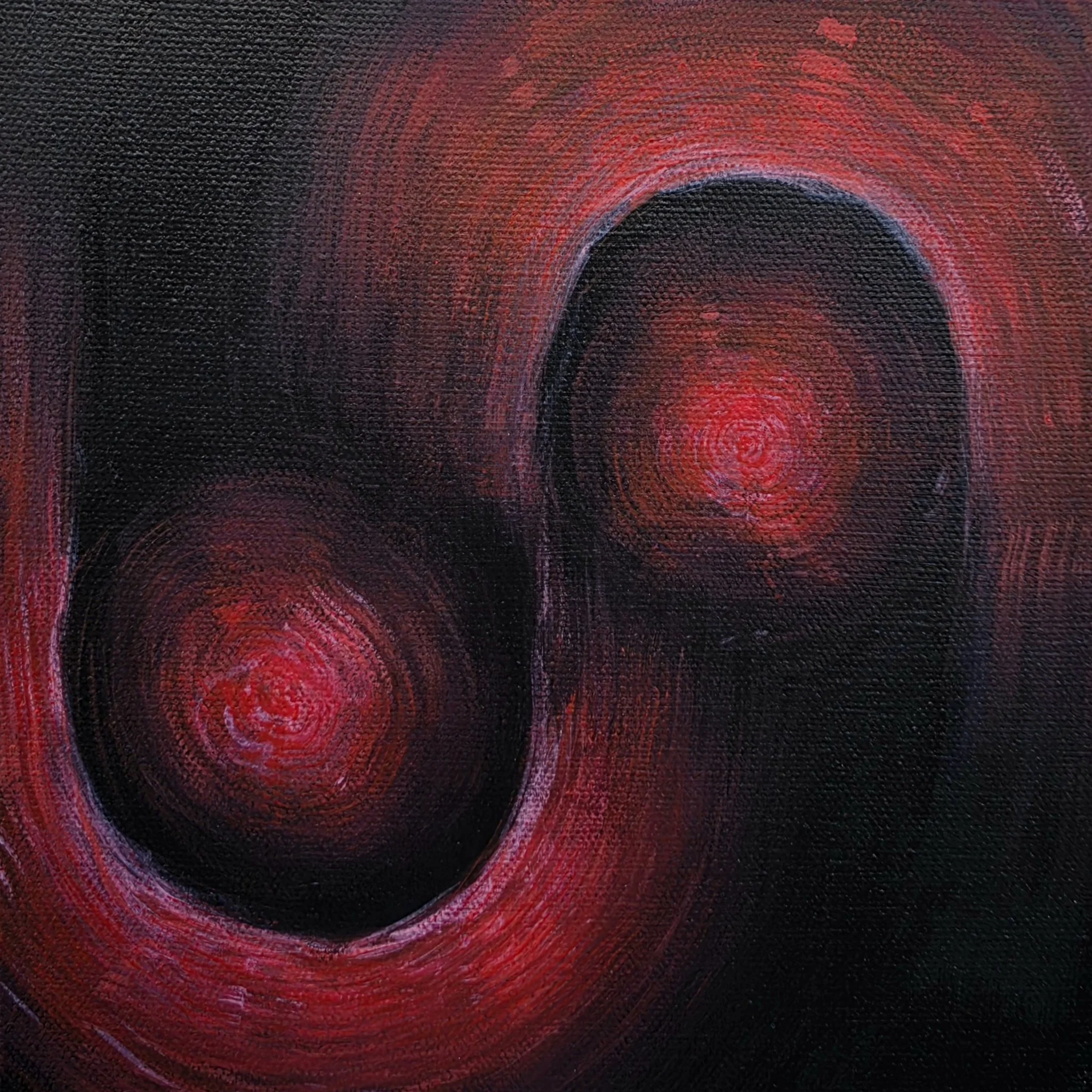 Close-up of a textured black surface with concentric red circles painted around a central black circle.