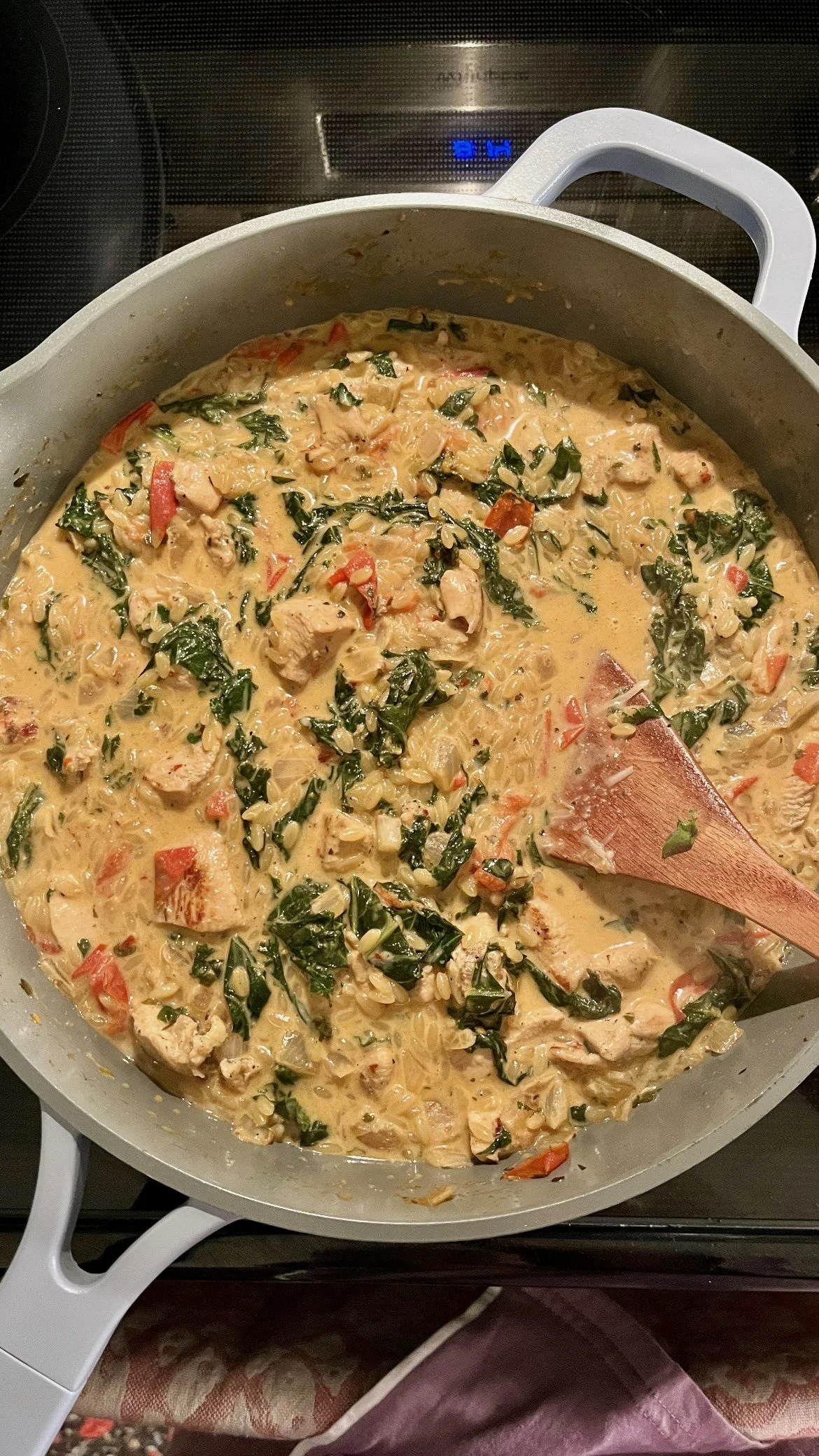 Creamy chicken and vegetable curry in a large pot on the stove, with a wooden spoon.