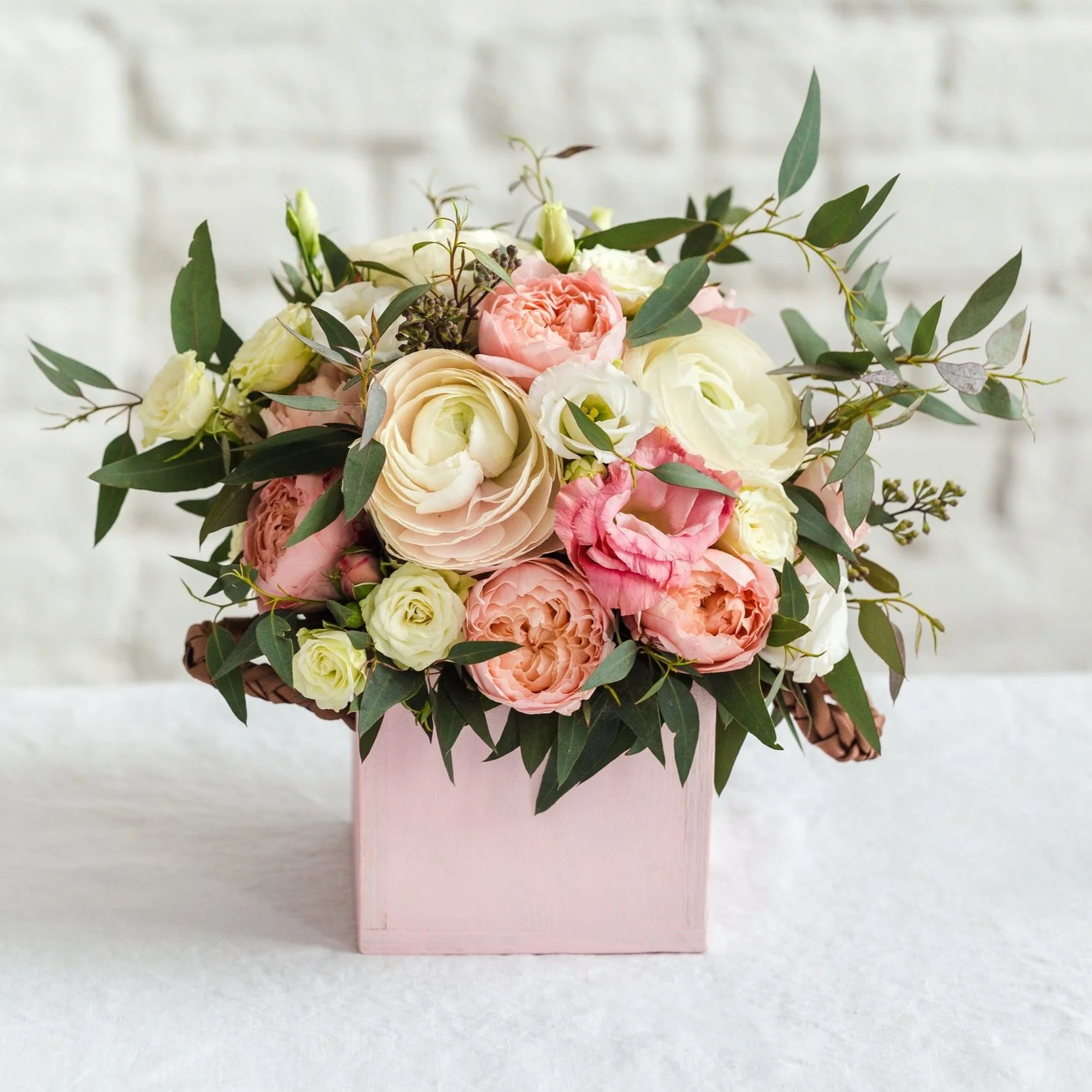 Floral arrangement with pink and white roses in a pink box.