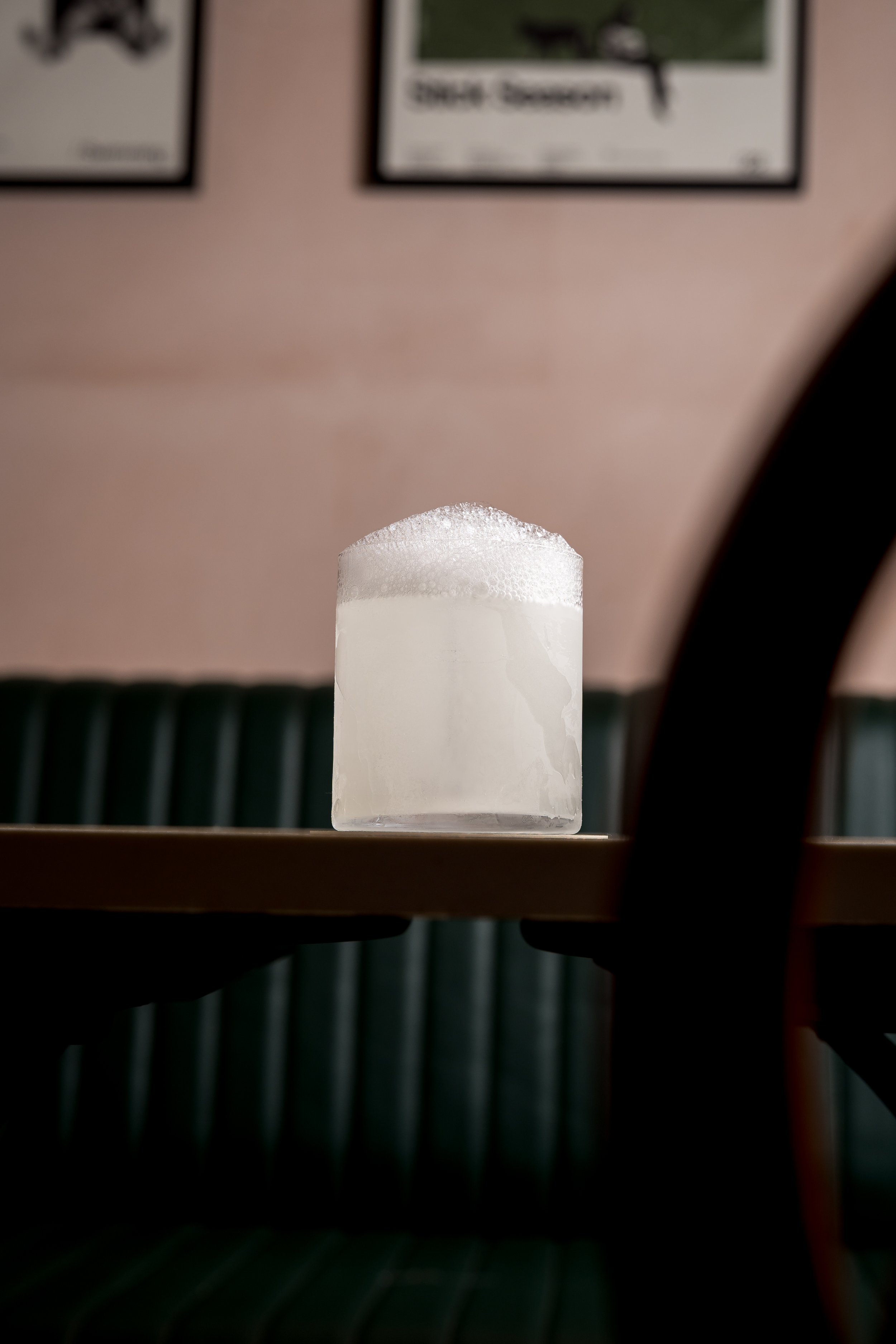 A glass of beer with foam on top, placed on a table in a restaurant or pub.
