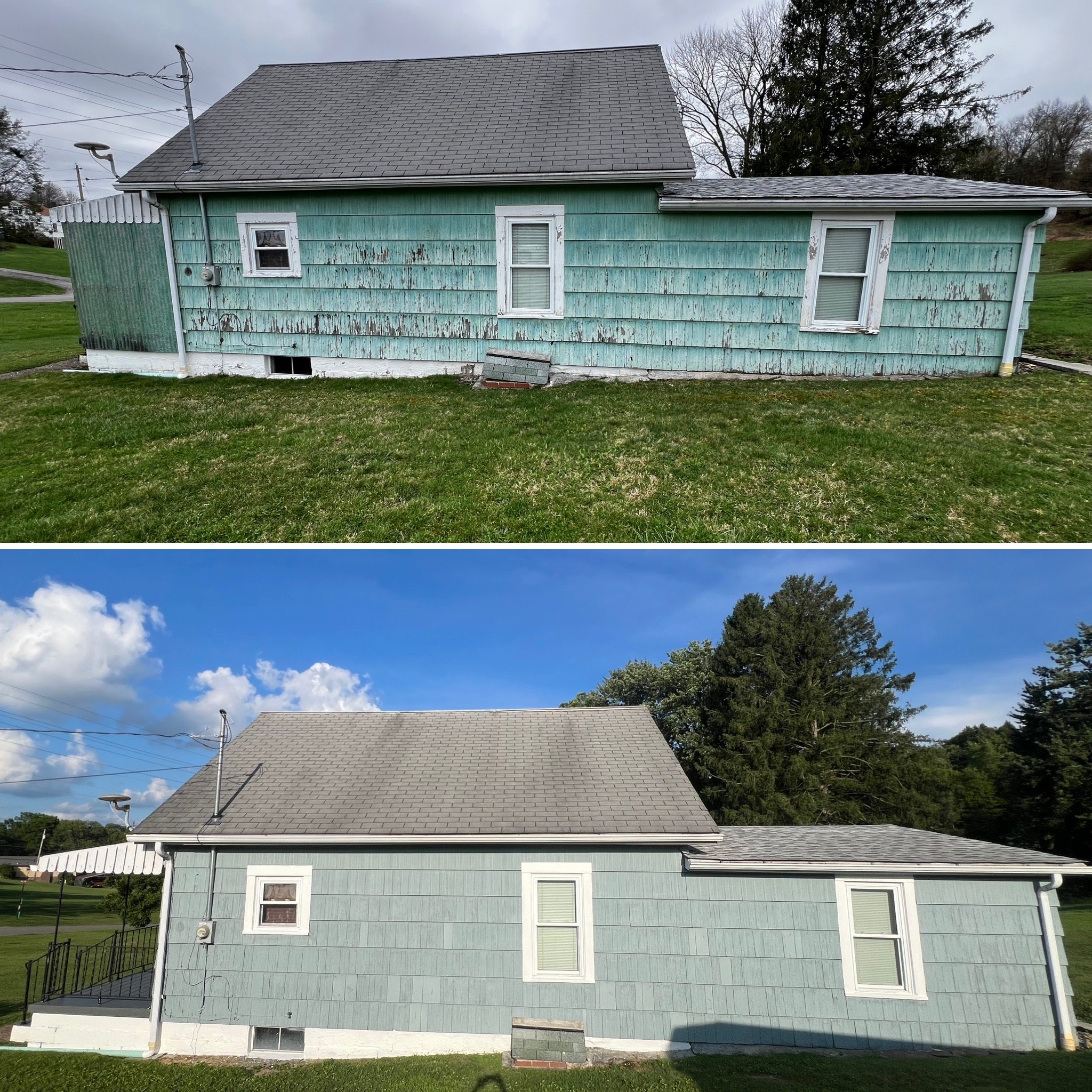 Side view of a light green house with boarded-up windows, peeling paint, and a damaged roof, with a lawn in the foreground and trees in the background.