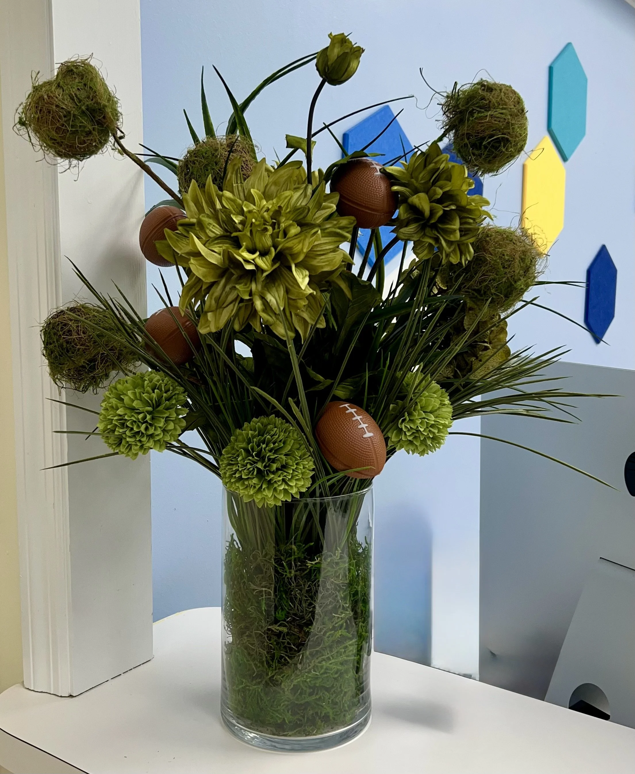 Finished DIY football floral arrangement styled against a blue wall.