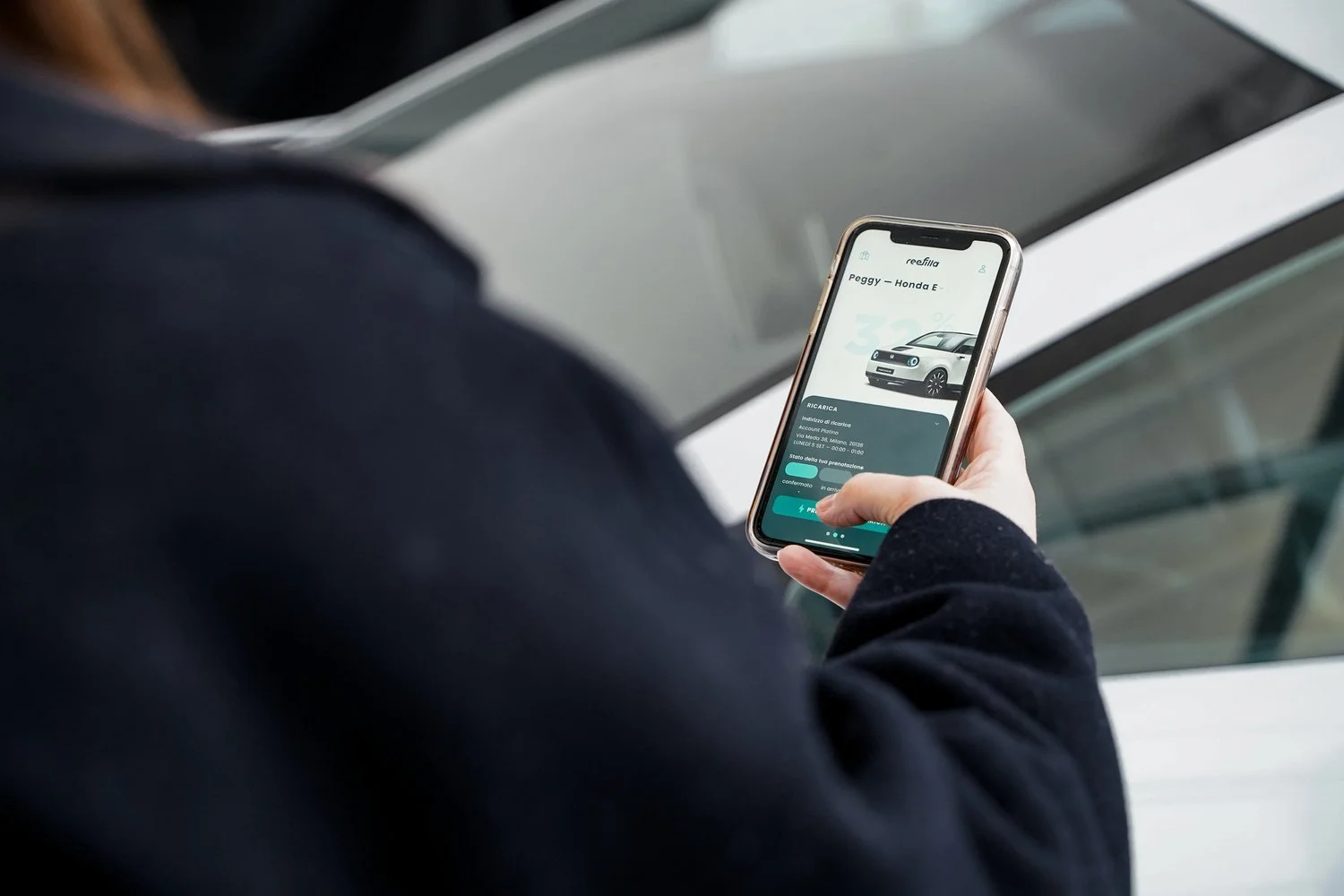 Person using a smartphone app next to a car
