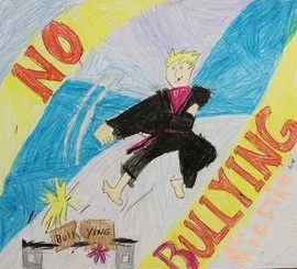 Child's drawing of a person in a black and pink martial arts uniform kicking a box labeled 'Bully' with yellow hair and an angry expression, with the words 'NO BULLYING' written in red and yellow.