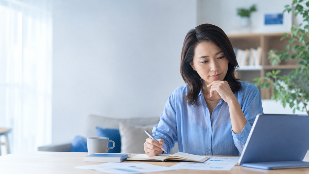 Japanese woman preparing for TOEIC at home with a laptop and study notes