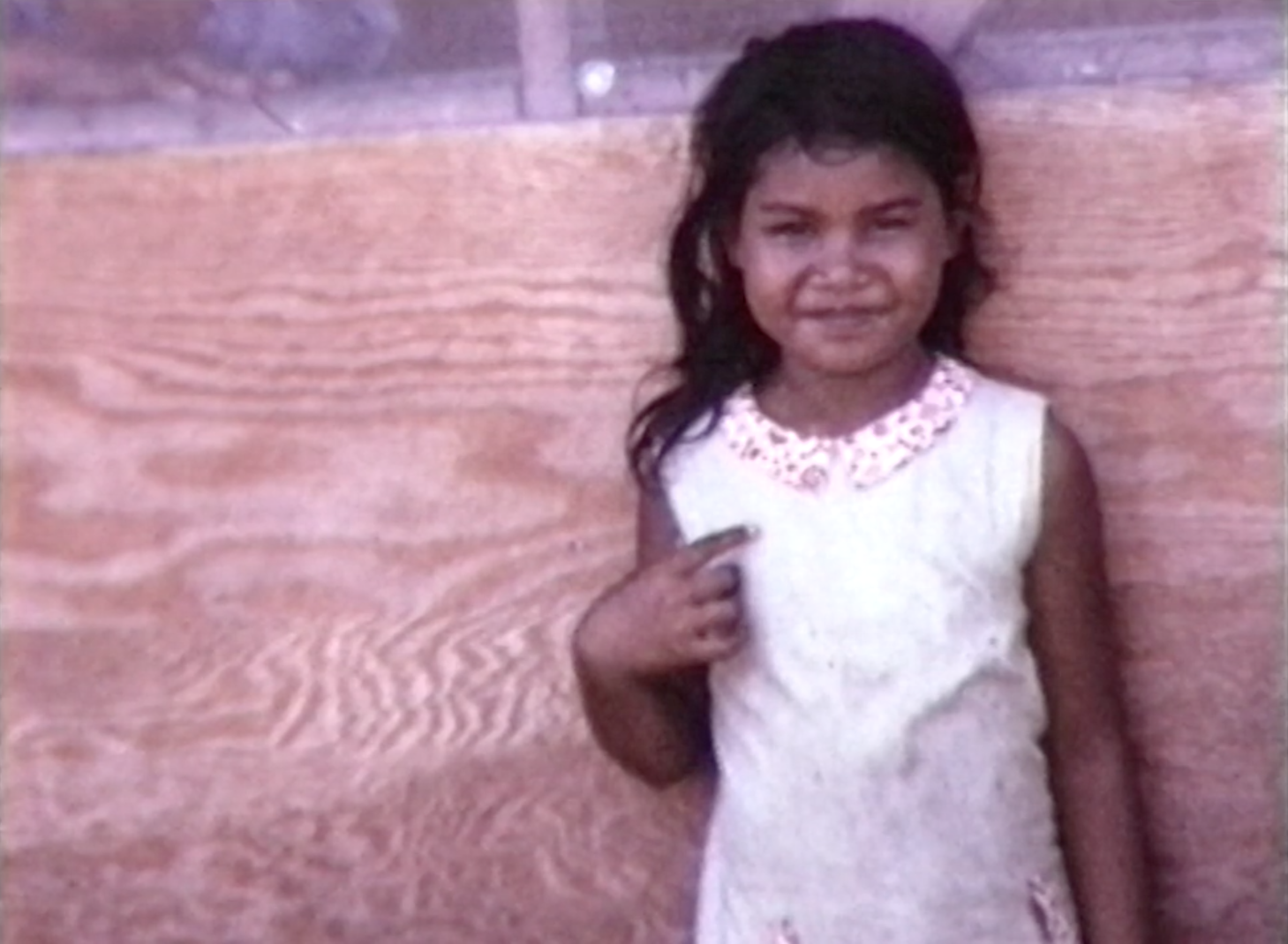 A grainy image of a young girl half-smiling at the camera