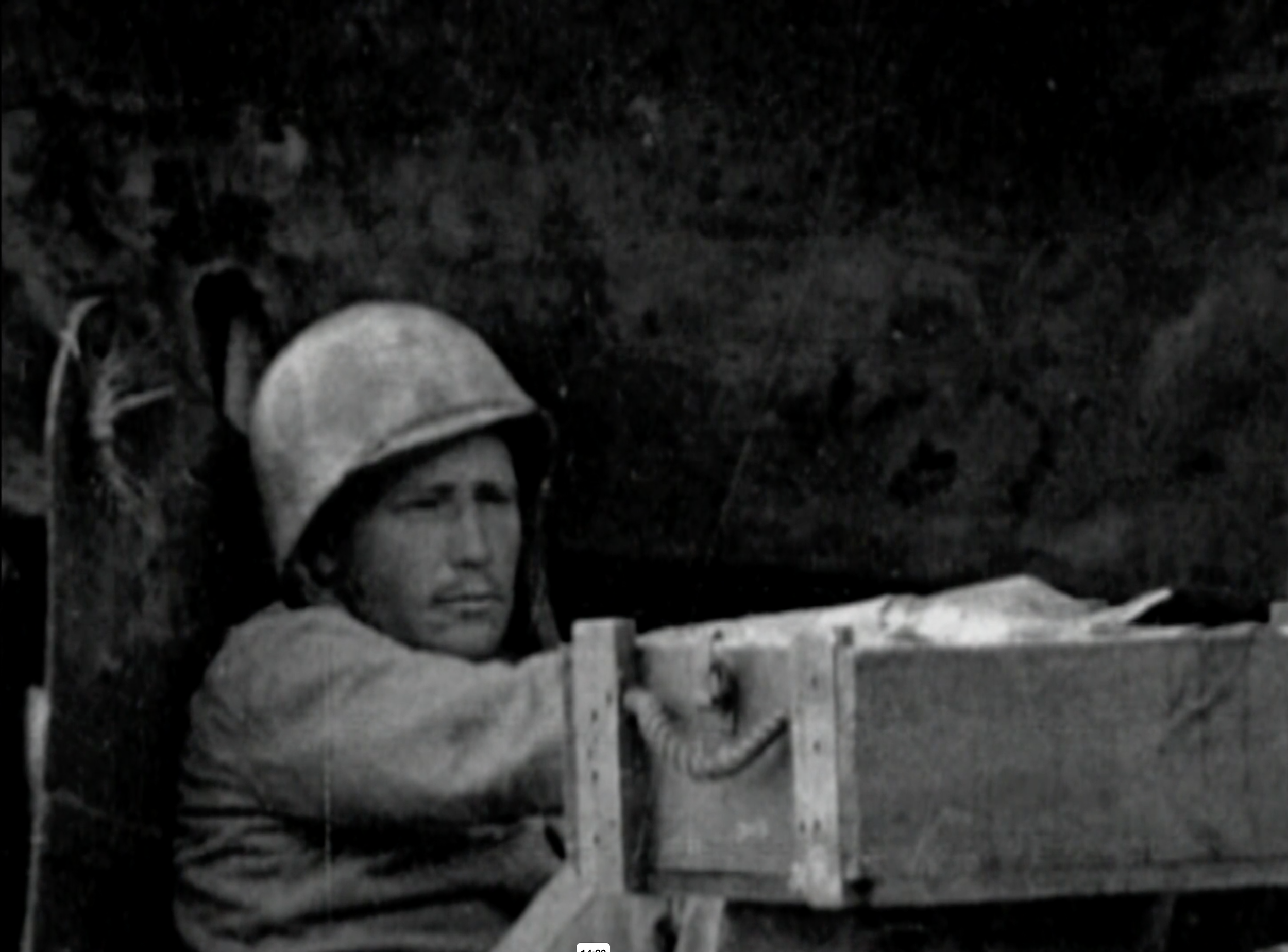 A black and white image of a man with a helmet on looking into the distance