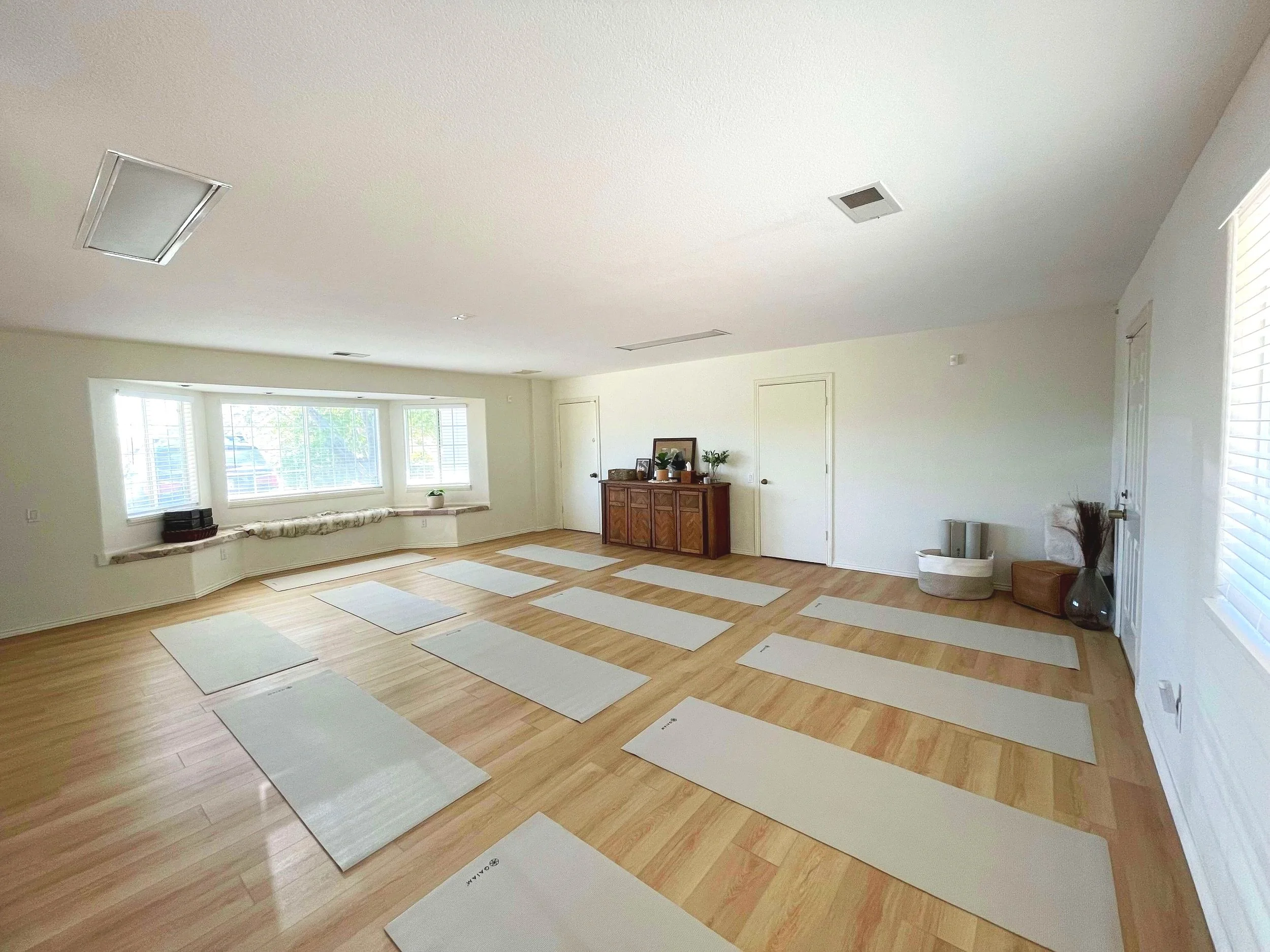 13 yoga mats spread across the floor of a large room.