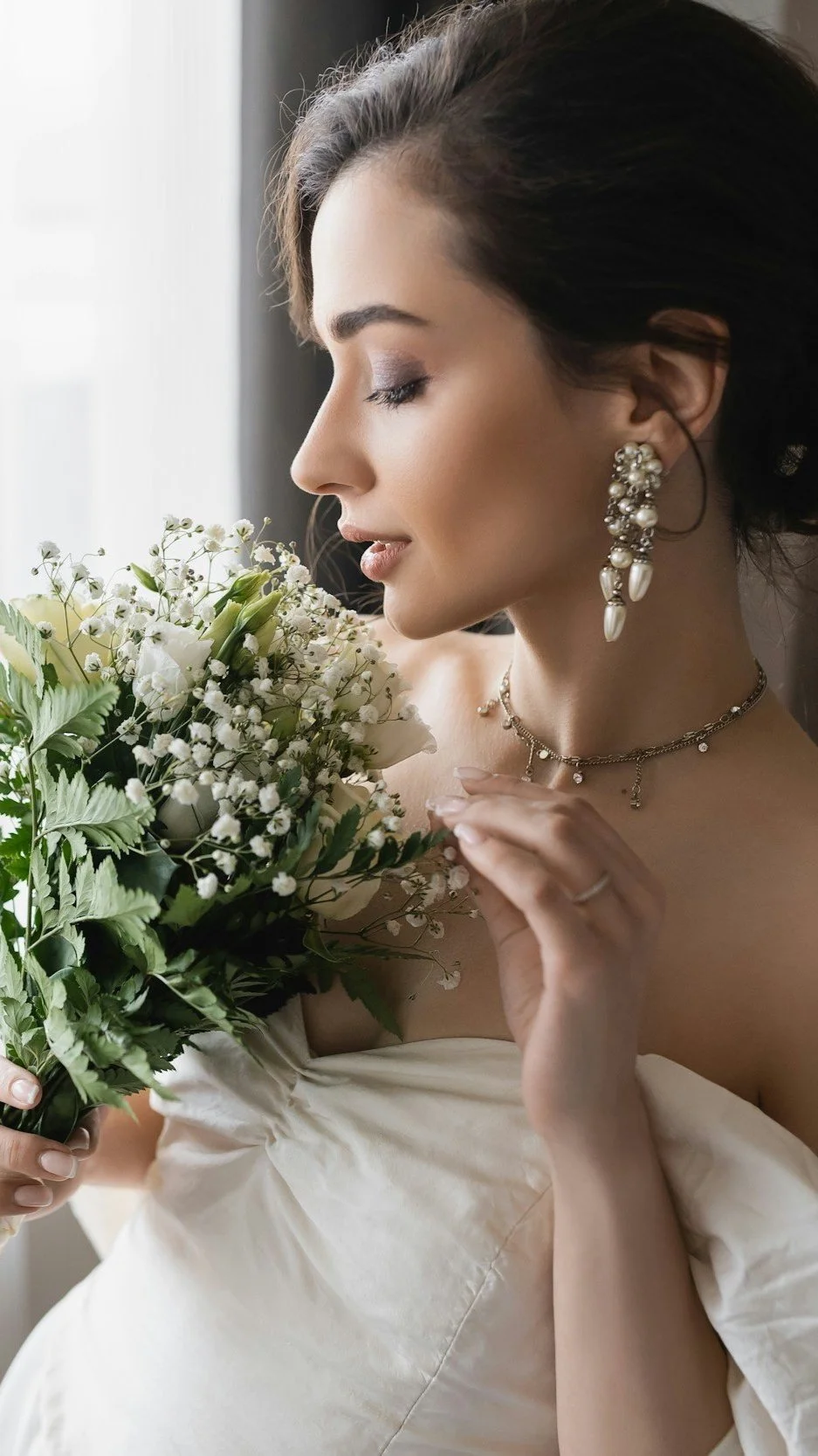 Woman in white dress holding a bouquet of flowers near her face