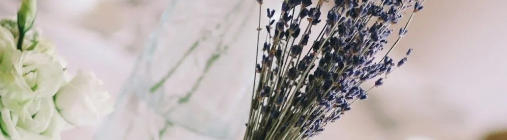 Close-up of a bouquet featuring dried lavender and white flowers in a glass container.