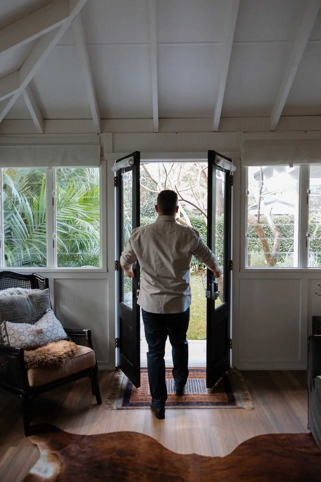 Scenic view of a large lake surrounded by green hills and tall mountains in the background, overcast sky.