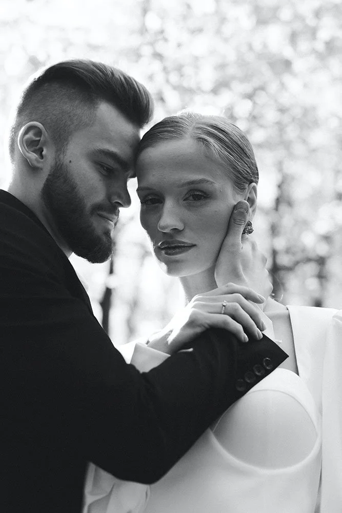 Black and white photo of a couple embracing, with a focus on the woman's face and the man's affectionate gesture.