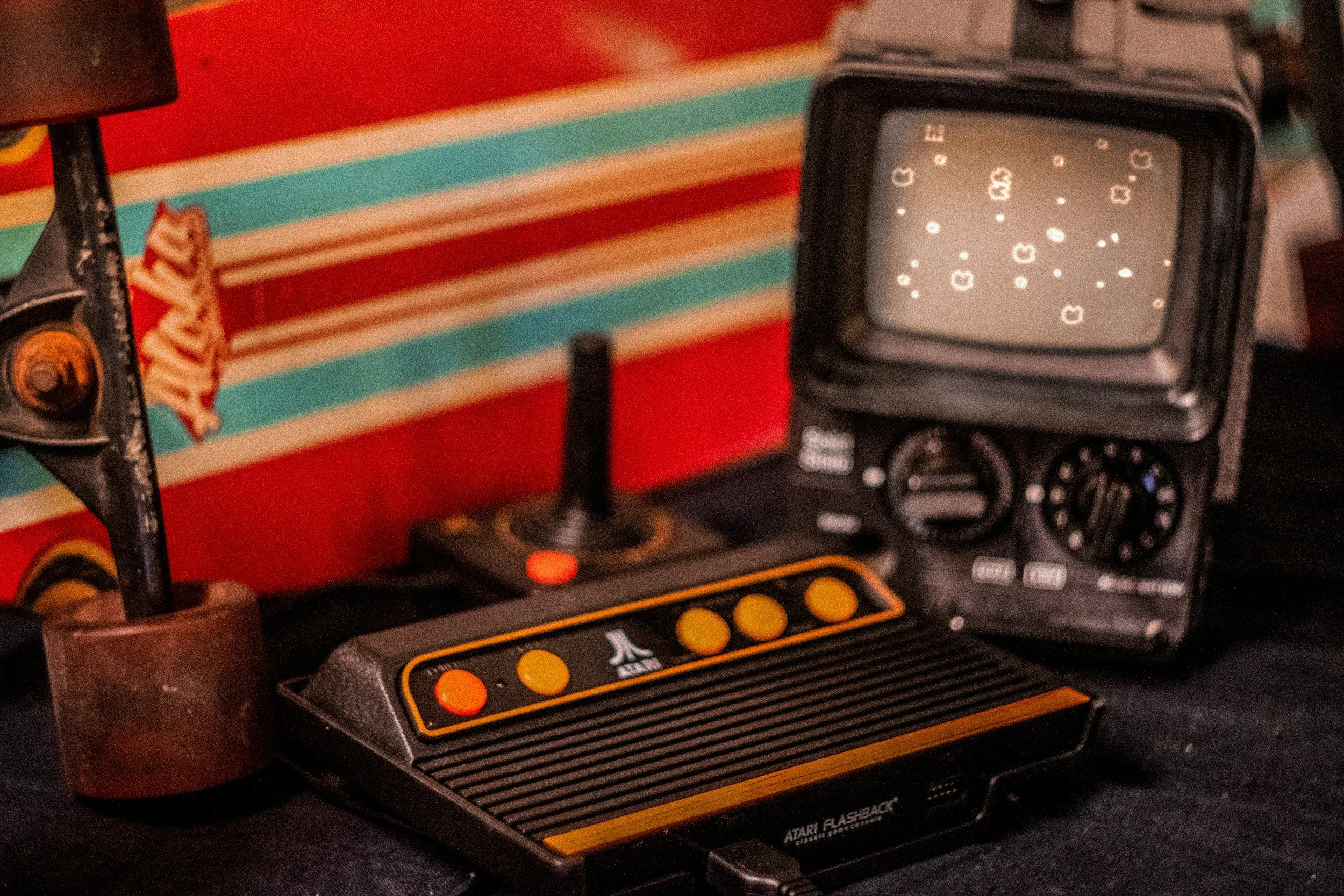 Vintage Atari Flashback gaming console on a red background next to a small retro TV screen, evoking play, fun, and nervous system regulation valued in Love & Moxie’s approach.
