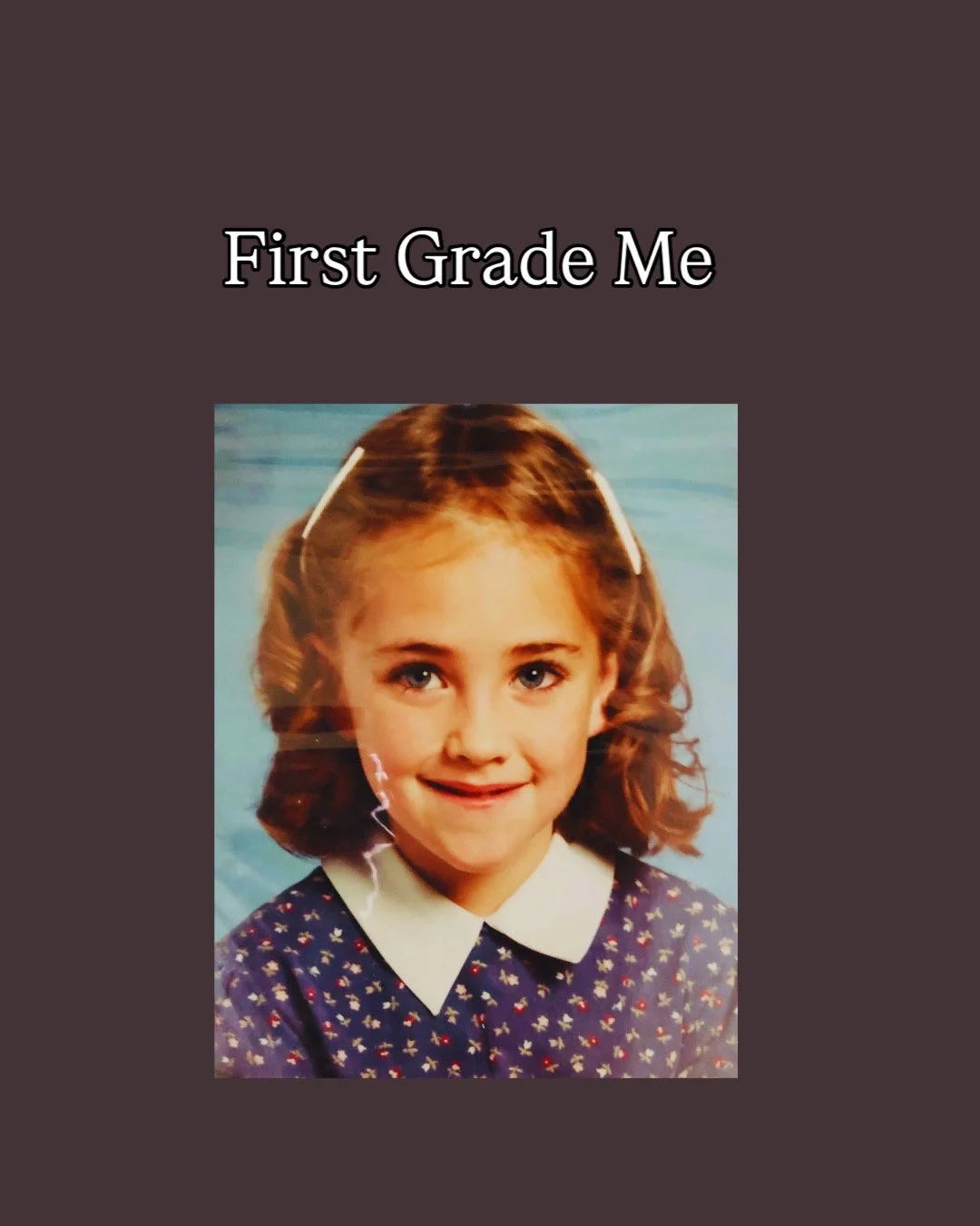 A young girl with shoulder-length curly brown hair, wearing a dark blue dress with a white collar, smiling at the camera. The text 'First Grade Me' is above her head.