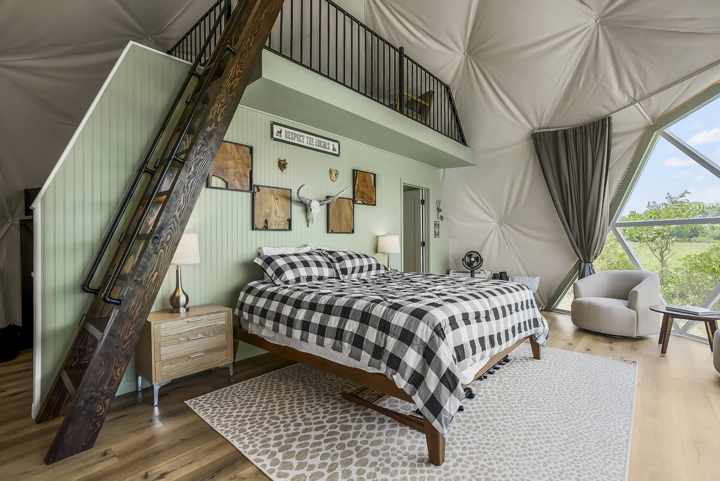 Wander Inn dome interior with a king bed, loft stairs, and curved dome ceiling