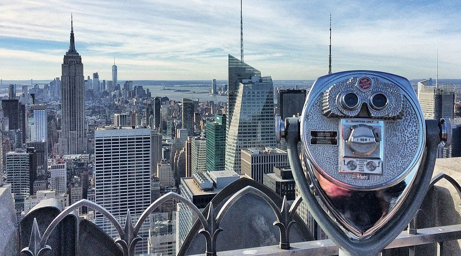 Veduta dello skyline di New York con la Torre di Empire State in primo piano e un telescopio da osservazione.