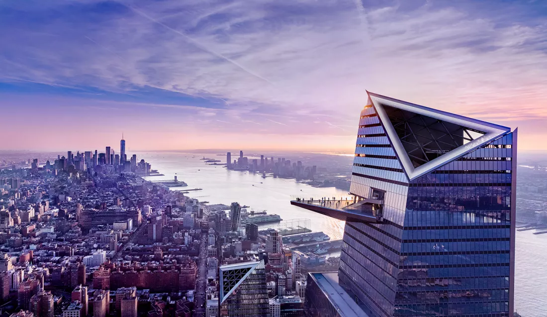 Veduta aerea di New York City al tramonto con un grattacielo moderno con forma triangolare e osservatorio con persone sulla terrazza