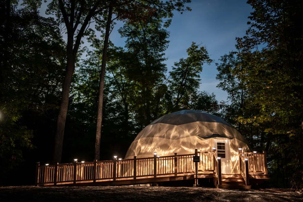 Glowing geodesic dome accommodation lit under the evening sky.