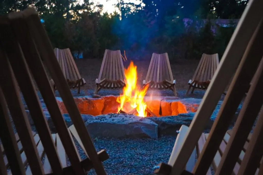 Evening fire circle gathering space surrounded by handcrafted wooden chairs.