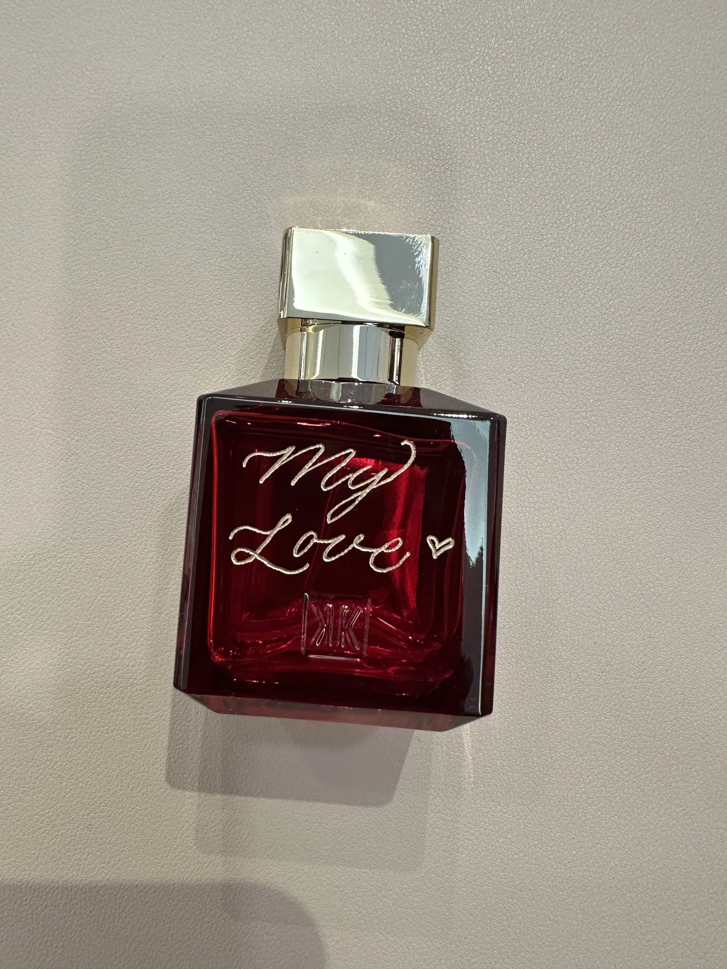 A red perfume bottle with a silver cap and the words "My Love" written in cursive on the front.