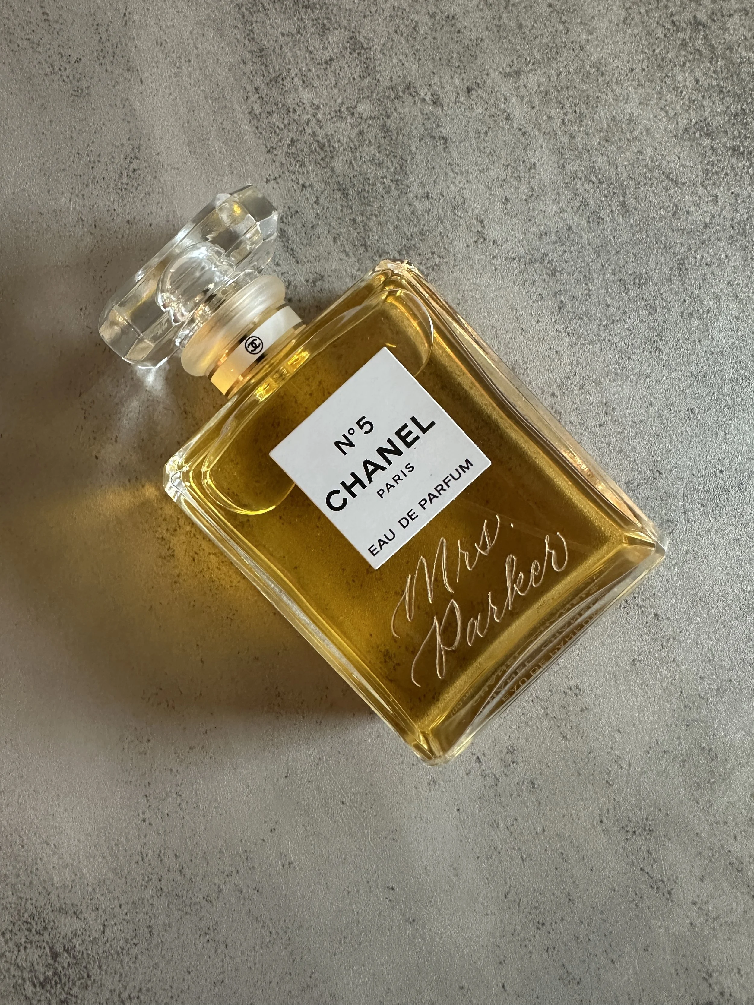 Engraved Chanel No 5 perfume bottle. "Mrs. Parker" engraved with gold fill on grey background.