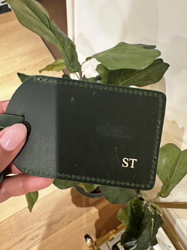 Green leather luggage tag with the initials 'ST' in gold monogram on the bottom right corner.