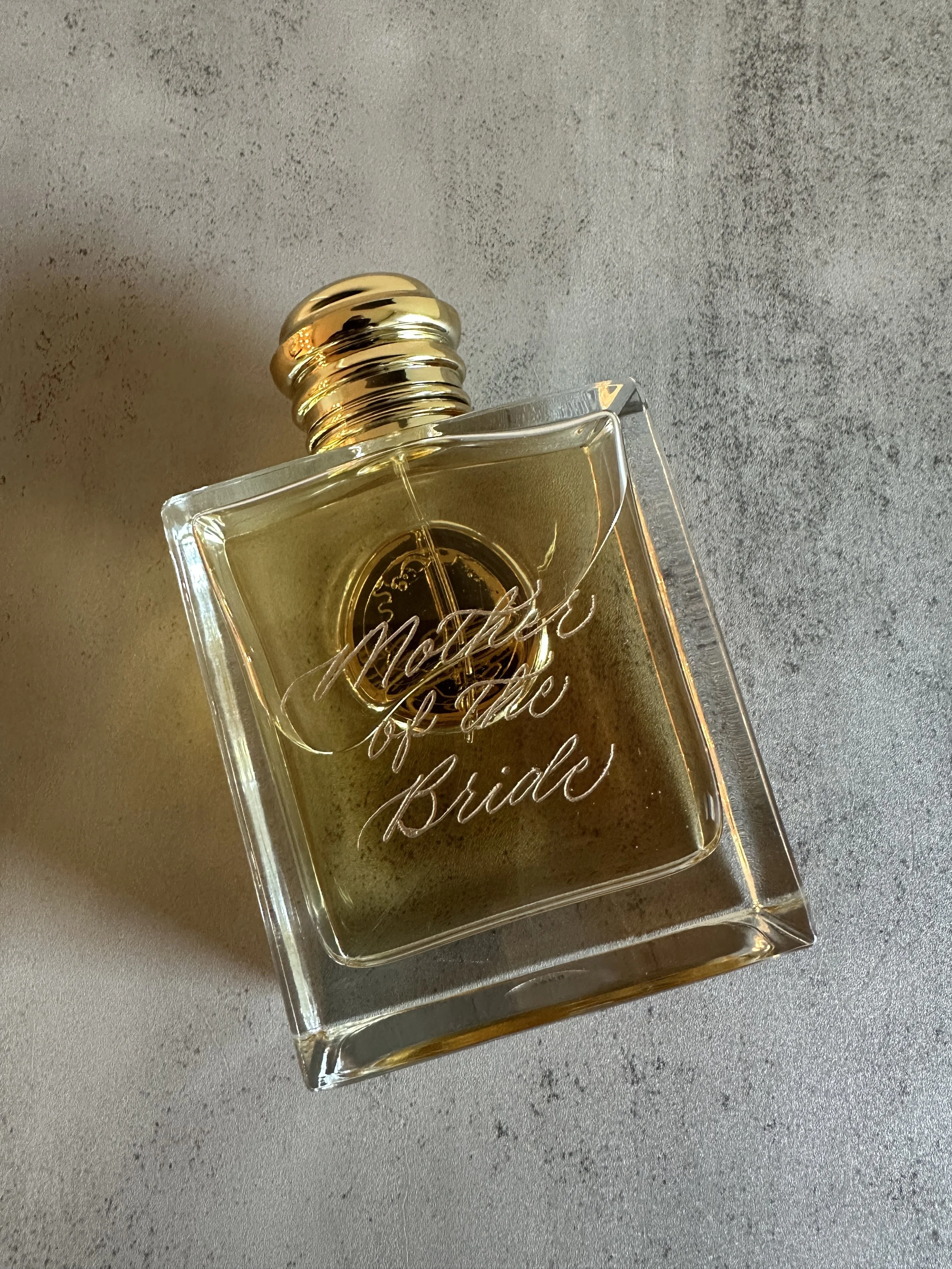 Engraved fragrance, "Mother of the Bride," in gold lettering on a perfume bottle. 