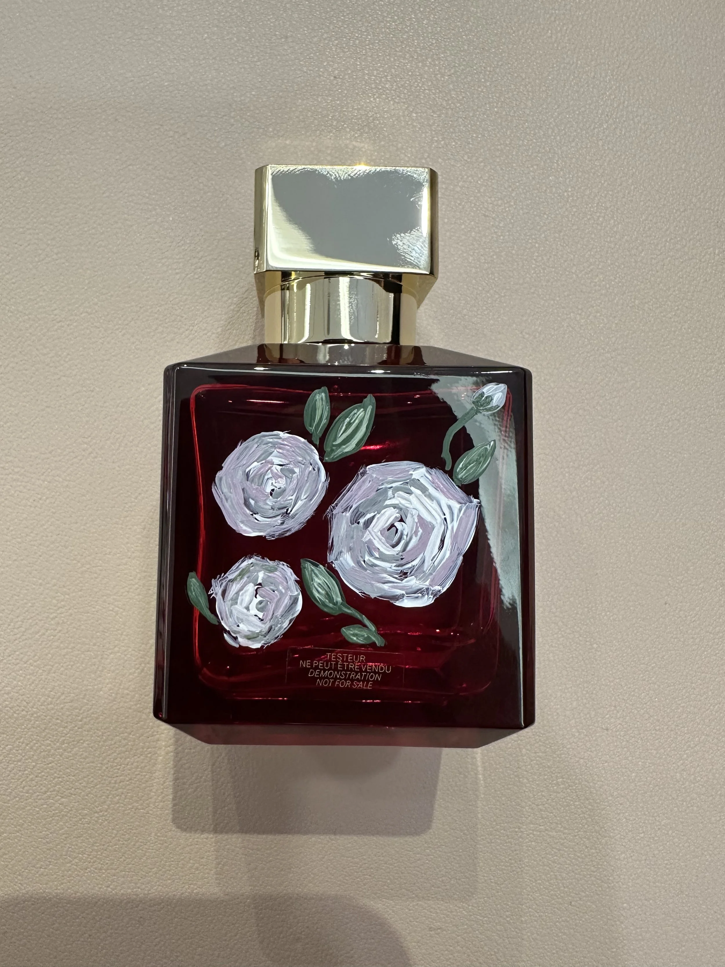 Red perfume bottle painted with three pink roses.