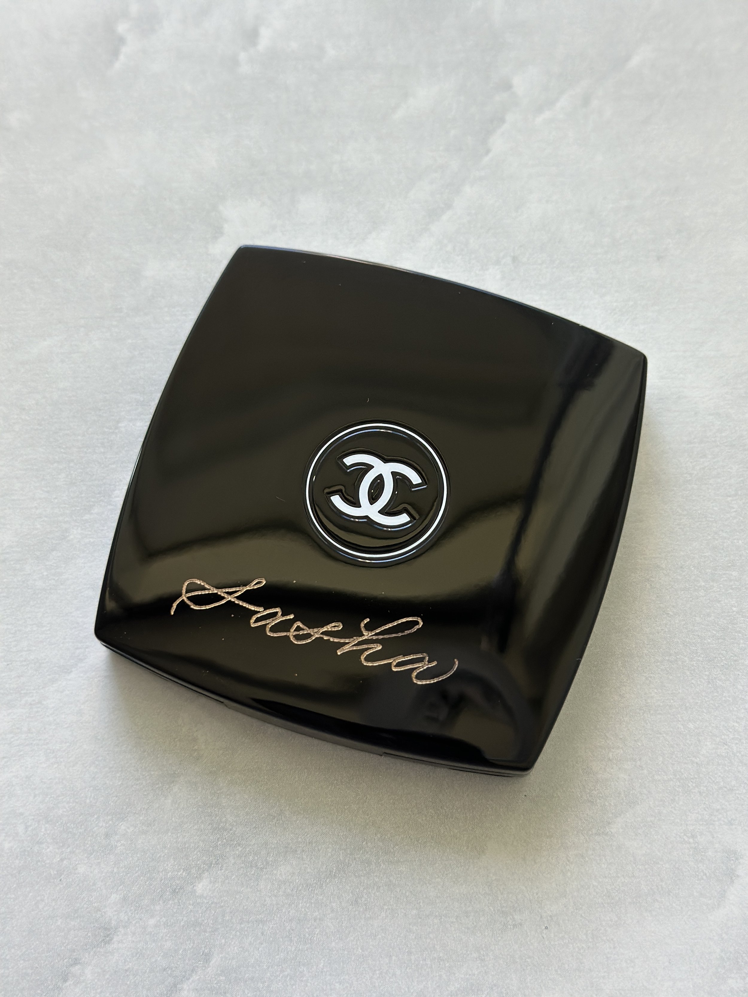 Black Chanel compact mirror with the name "Sasha" engraved.