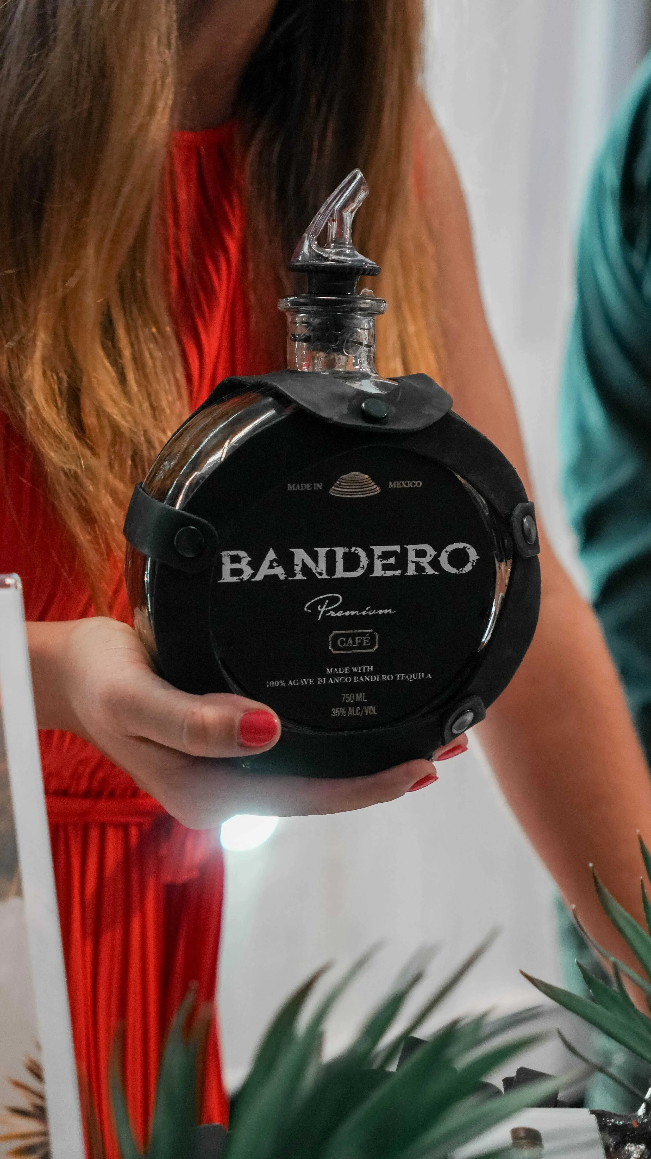 Person holding a bottle of Bandero tequila with a black label and glass stopper.