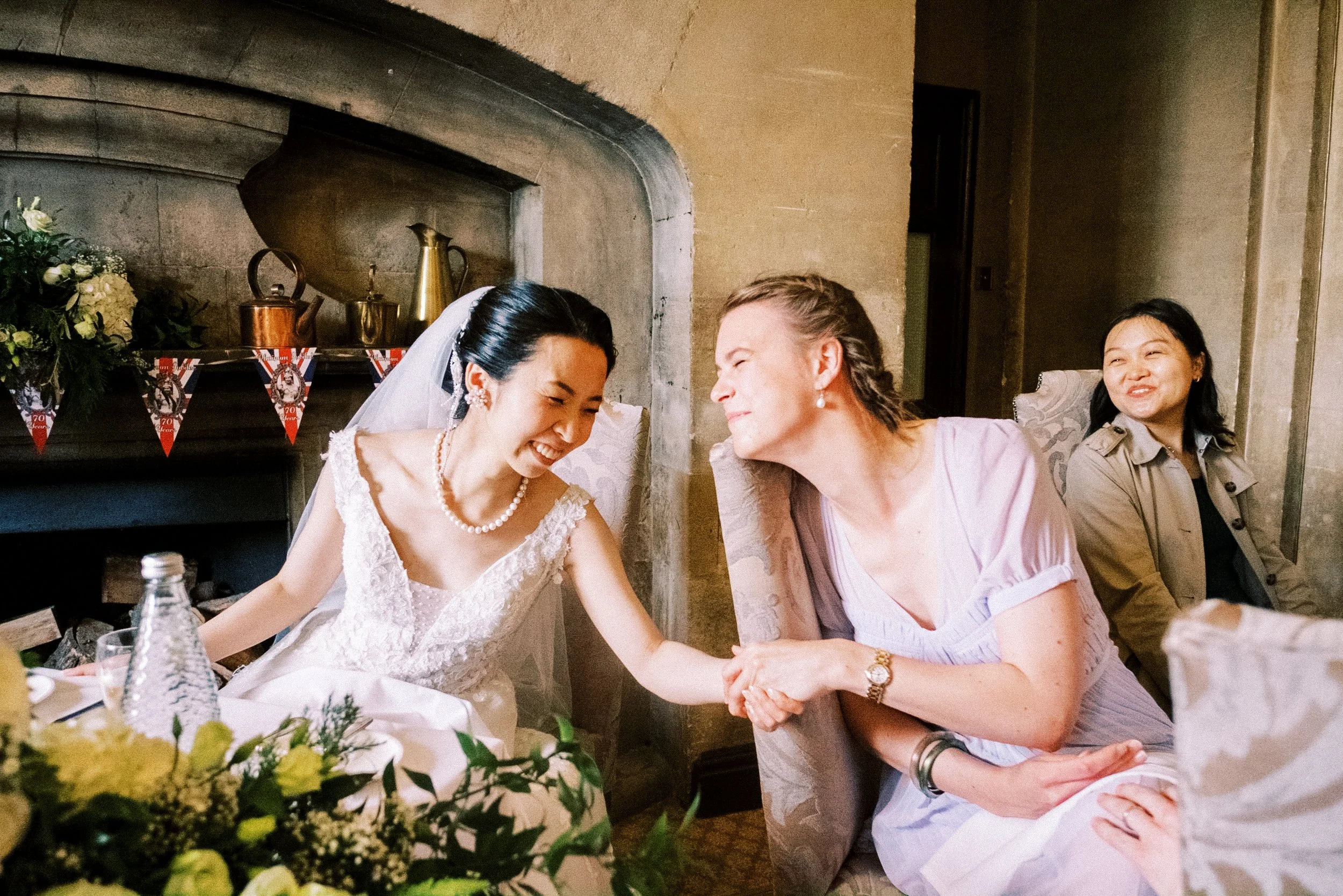 Bride celebrates with bridesmaid during wedding breakfast