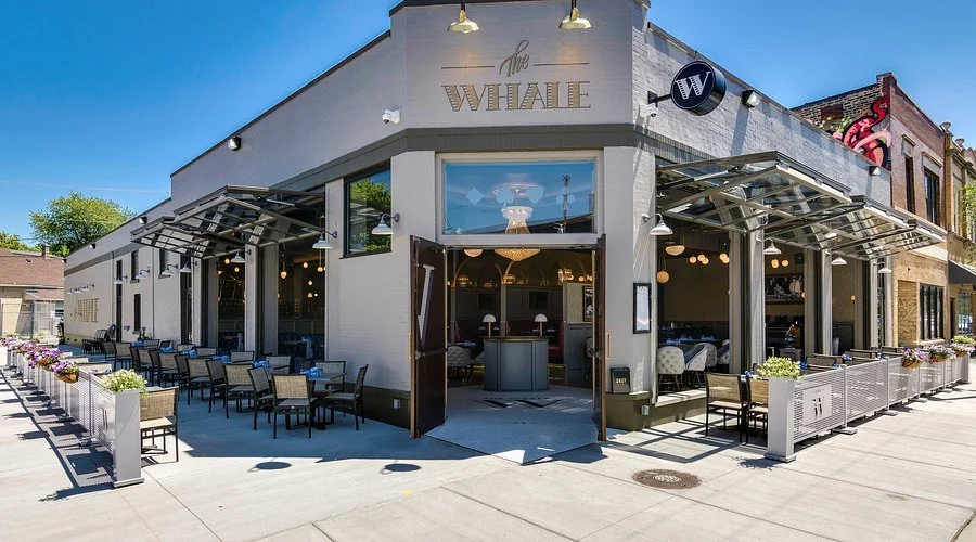 Exterior of a restaurant named 'The Willie' with outdoor seating, potted plants, and large glass windows.