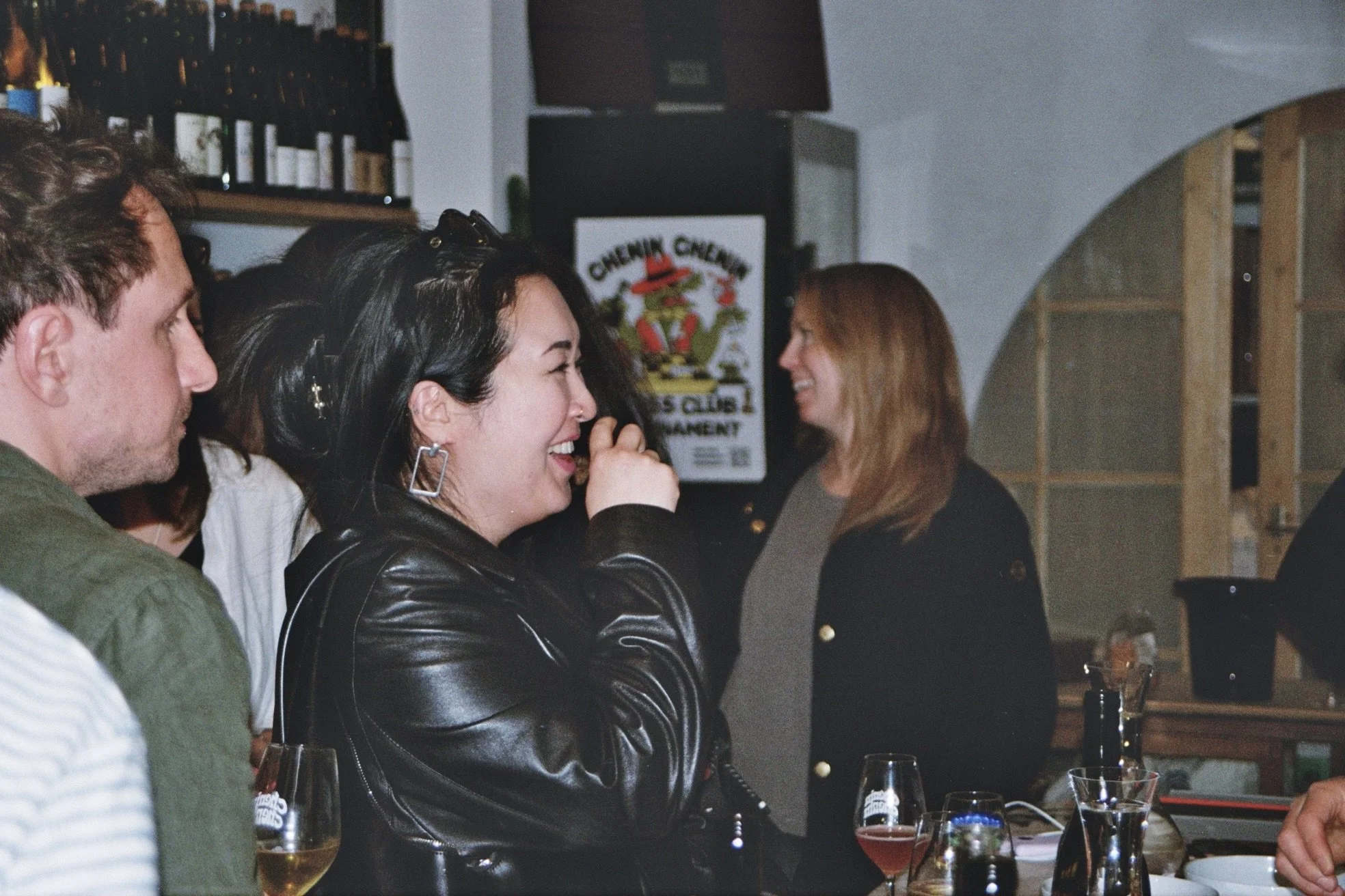 A group of people socializing at a bar, smiling and enjoying drinks.
