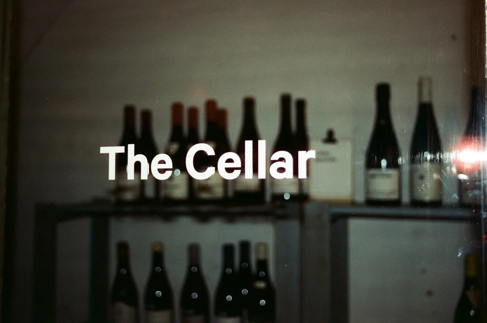 Shelf with wine bottles and a sign that reads 'The Cellar'