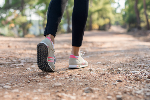 Persoon die wandelt op een modderig pad in het bos, alleen de benen en schoenen zichtbaar.