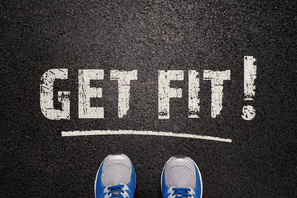 Gezichtspunt op een asfaltweg met de tekst 'GET FIT!' geschilderd en een paar sportschoenen onderaan.