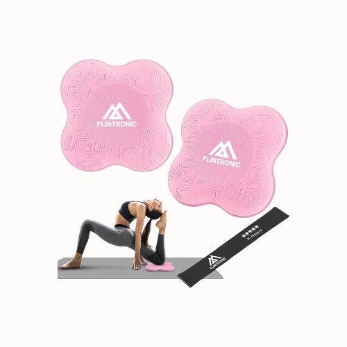 Een vrouw die yoga doet op een roze yogamat met twee andere roze yoga mats en een zwarte strap op de vloer.